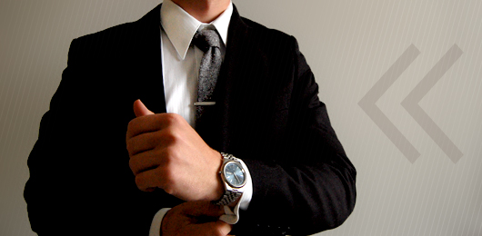 A man wearing a suit and tie holding his watch
