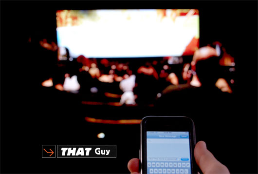 A person holding a cell phone at a movie theater