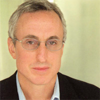 Gary Taubes wearing a suit and tie smiling at the camera