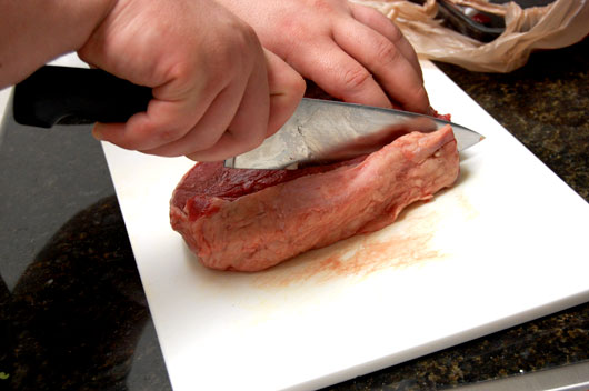 A piece of meat on a cutting board, with Stew and Beef