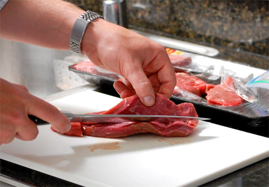 A person cutting beef on a table