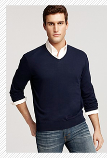A person standing posing for the camera in a v neck sweater