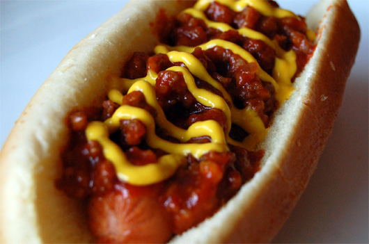 A close up of a hot dog on a bun covered in toppings