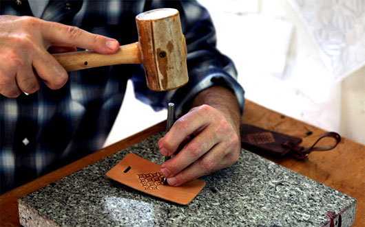 Man using a mallet on a leather wallet