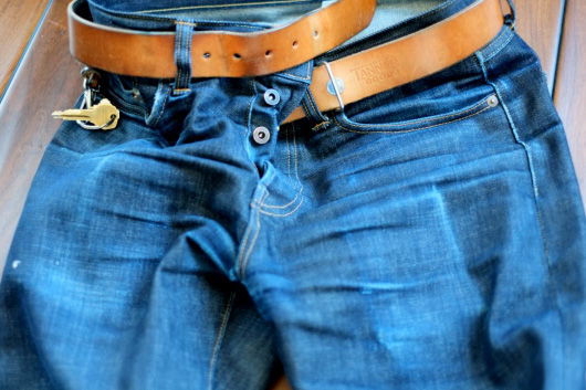 A pair of worn selvedge denim jeans with belt