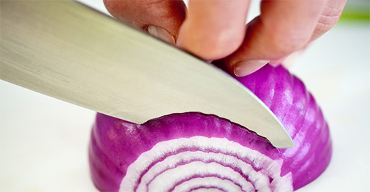 Knife cutting through onion