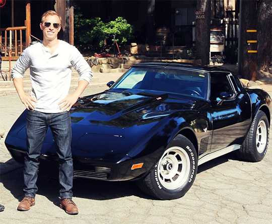 A man standing in front of a c3 corvette