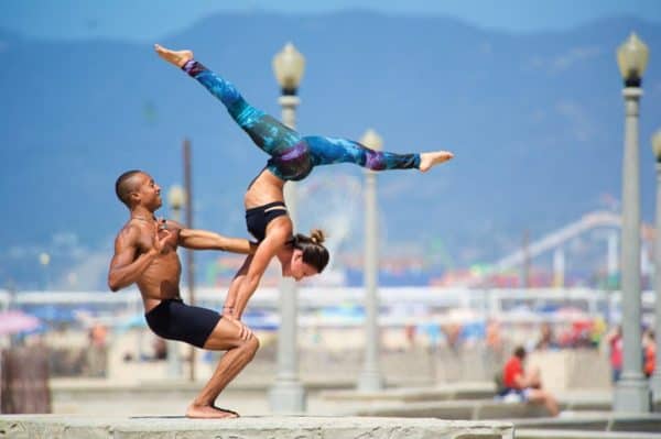 Fit couple practices acro yoga on the beach