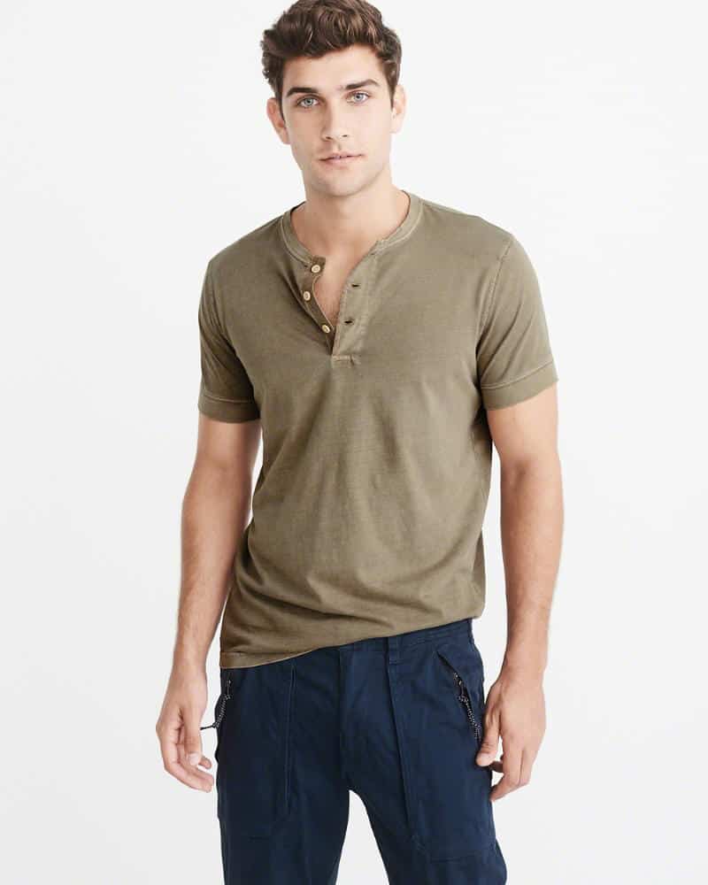 A person standing posing for the camera in a green henley