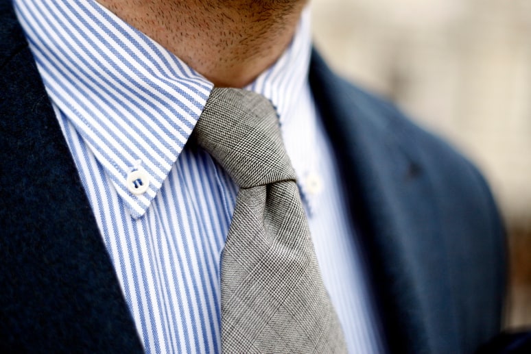 A close up of a man wearing a blue dress shirt and tie