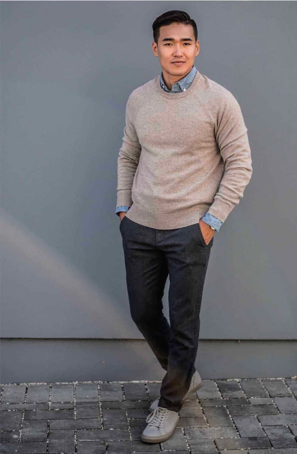 a man wearing proper length dress pants with a sweater and sneakers