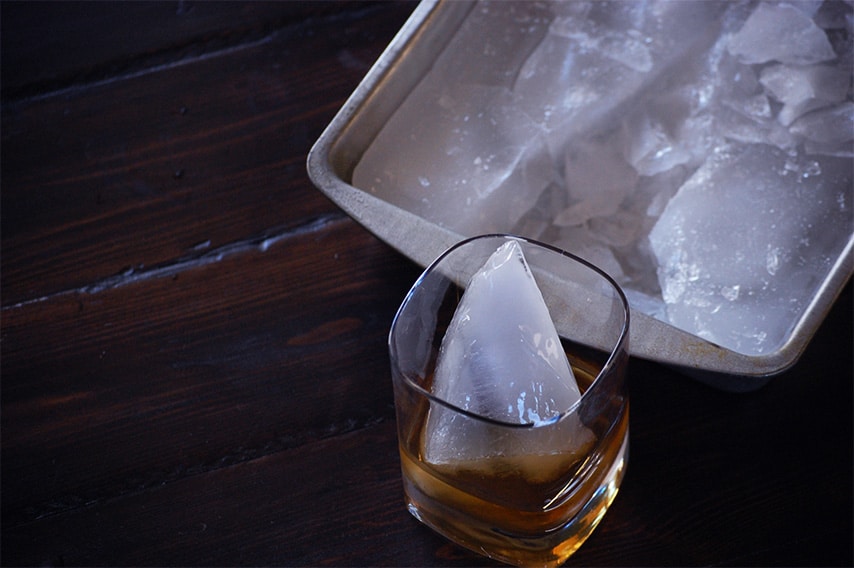 a cocktail glass beside a pan containing ice