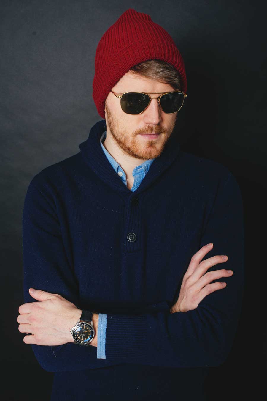 man in sunglasses, watch cap, and sweater