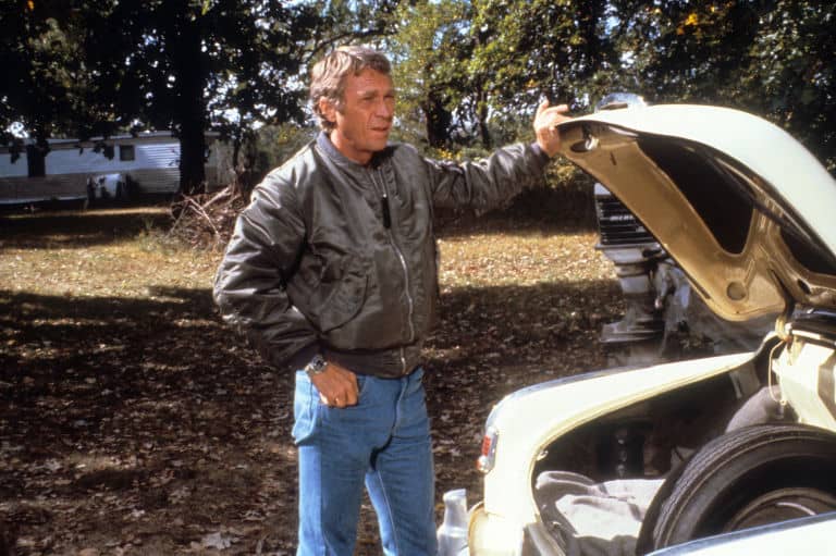 Steve McQueen standing in front of a car