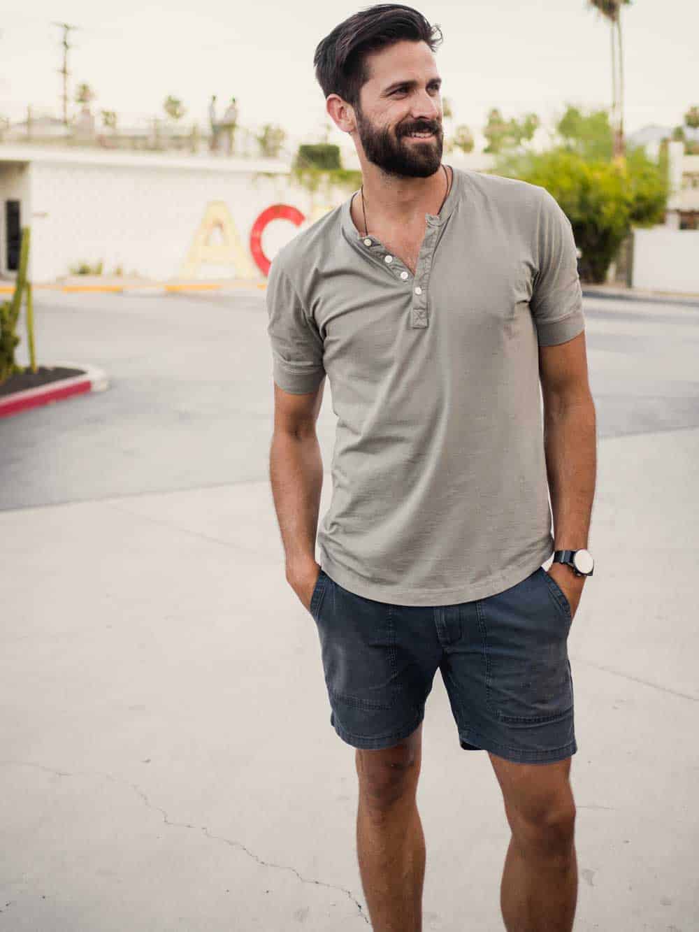 A man standing in a parking lot with a short sleeve henley