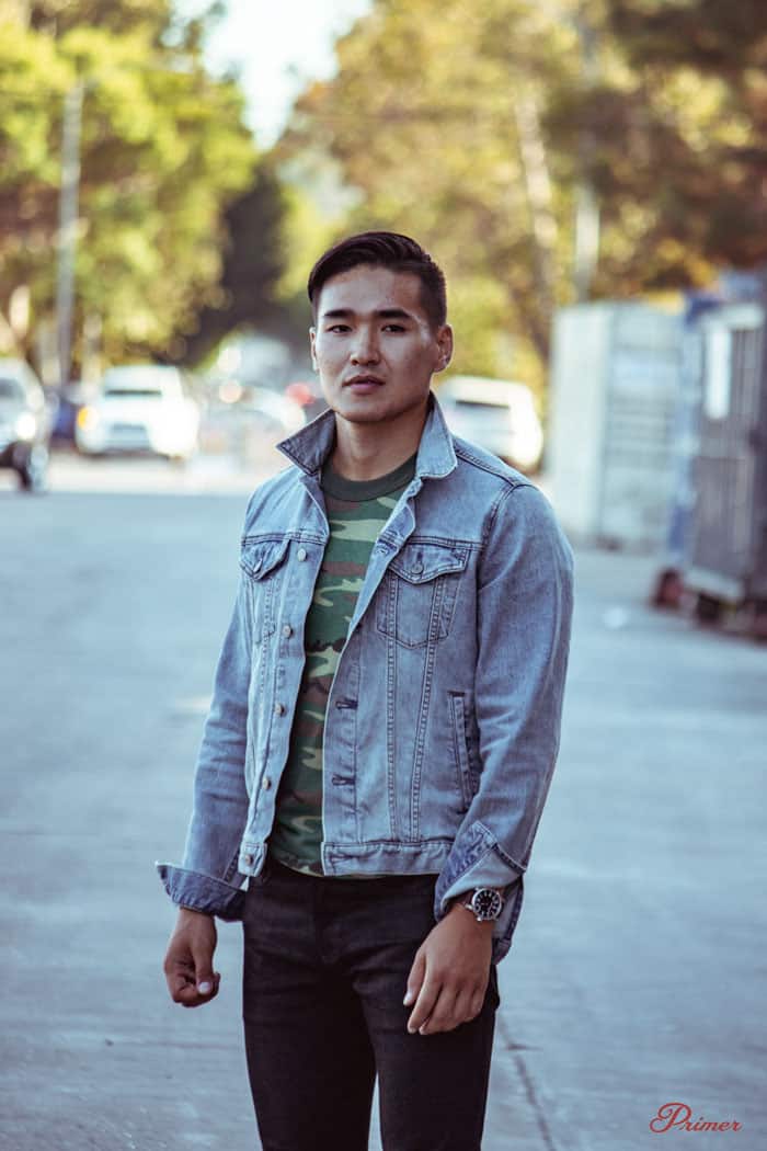 a man wearing a denim trucker jacket over a t-shirt with jeans and boots