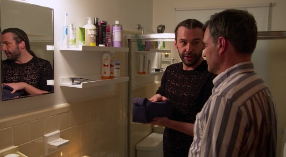 A man standing next to a sink, with Queer Eye