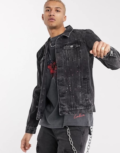 A person standing posing for the camera wearing a faded black denim jacket