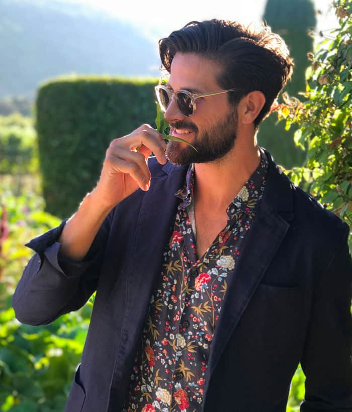 a man wearing a navy blazer over a floral shirt and sunglasses