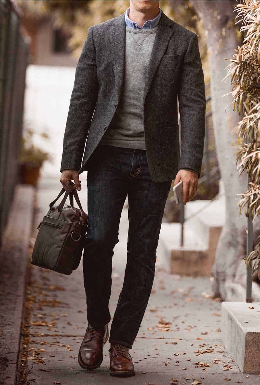 A man wearing a sportcoat and brown shoes walking on a sidewalk