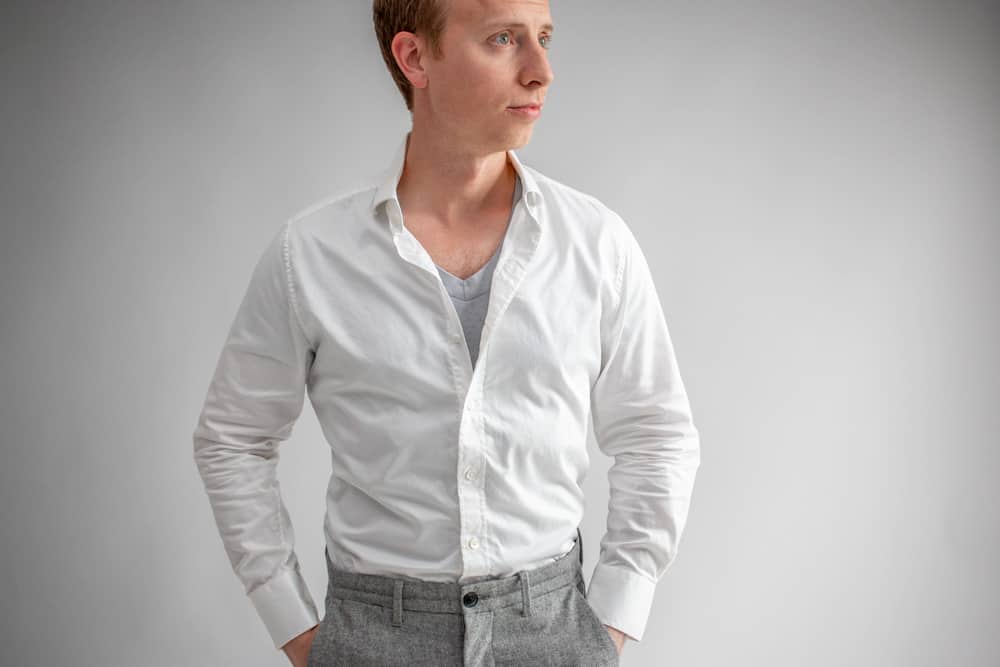 a man wearing a grey shirt under a white shirt to prevent see through 