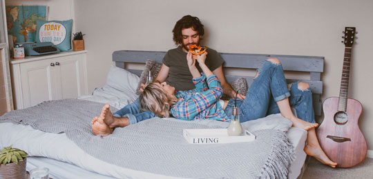 A woman and man sitting on a bed