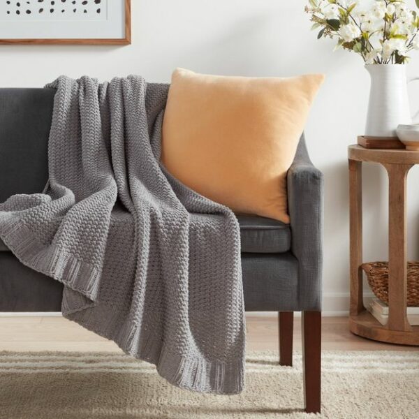 image of a gray throw blanket and yellow decor pillow on a couch