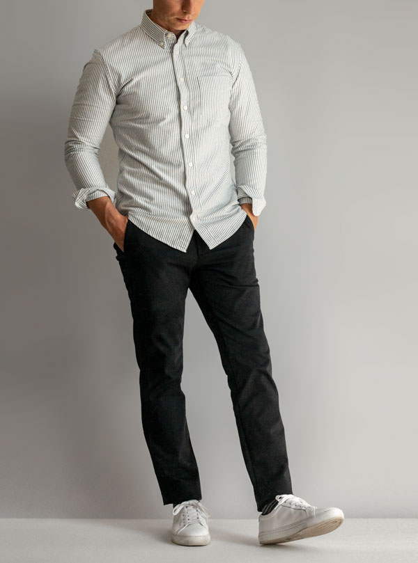 a man wearing an outfit from Everlane with a button up shirt, pants, and lace up sneakers