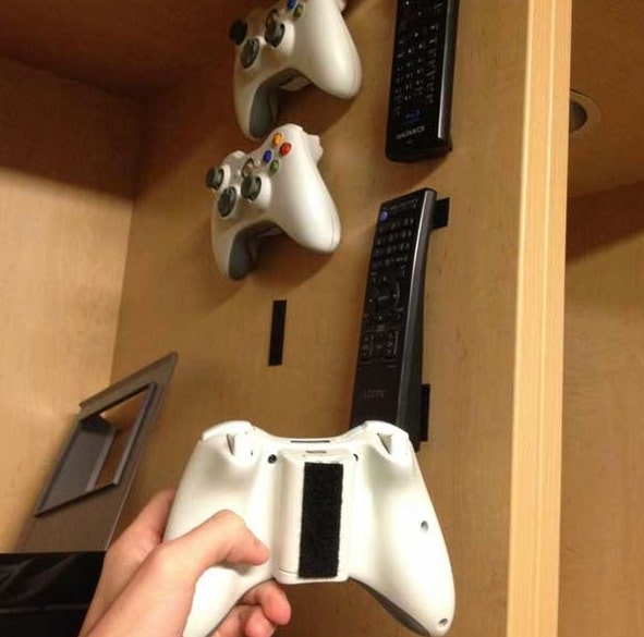 a space saving organization hack using velcro to hold and store remote controllers and game console controllers