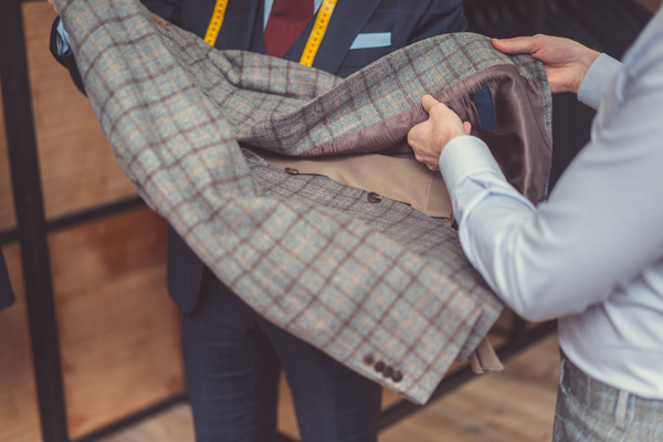 a tailor and a man holding a suit jacket for alternations