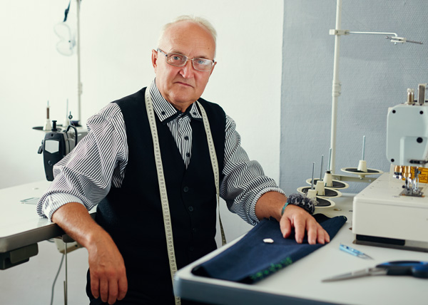 tailor sitting at sewing machine making alterations