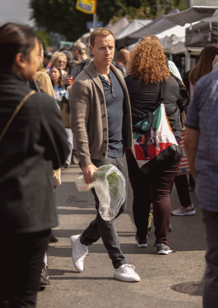 man wearing a brown shawl collar cardigan walking through a crowd