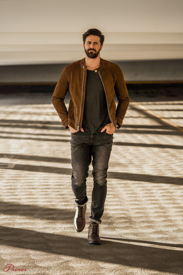 man wearing brown racer jacket with tshirt walking in garage