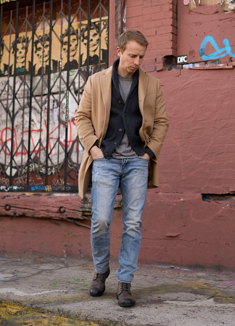 man wearing a camel topcoat with shawl collar sweater and t-shirt and jeans