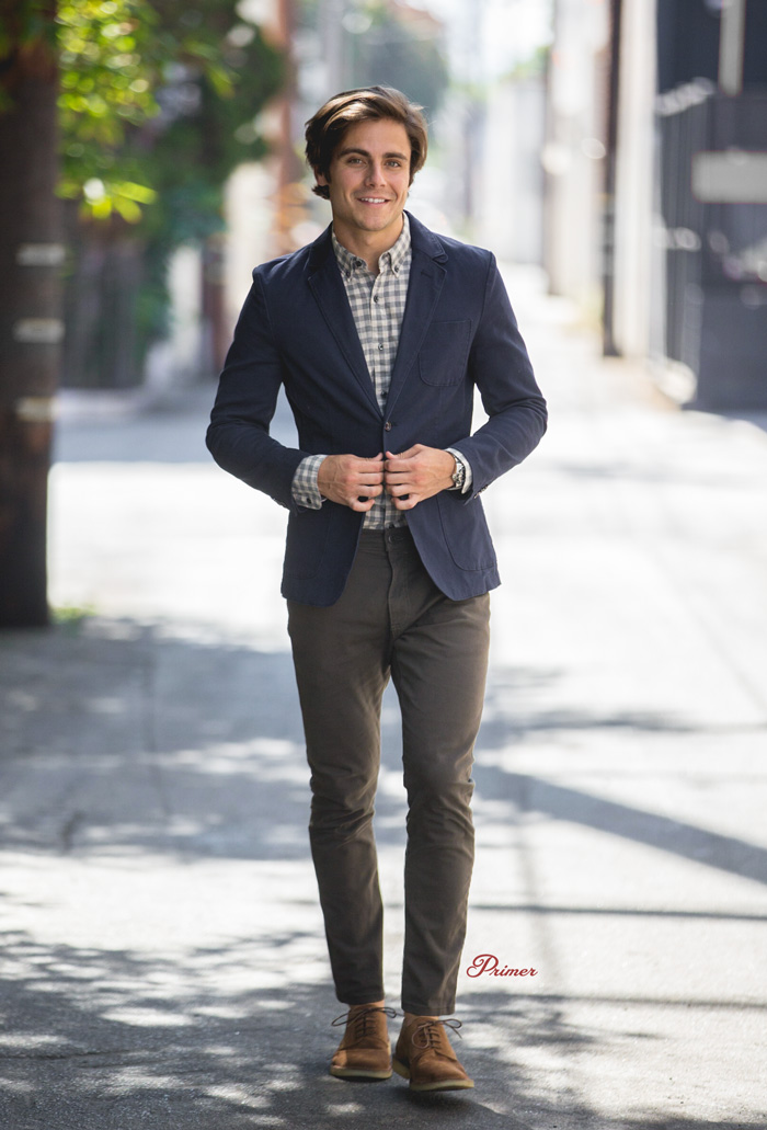 man wearing smart casual outfit with blue blazer, check shirt, brown pants, and suede shoes