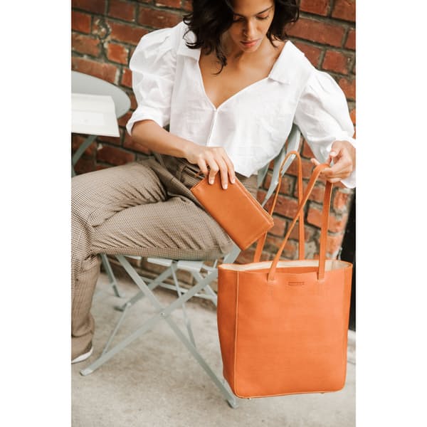 image of a woman holding an orange leather tote bag