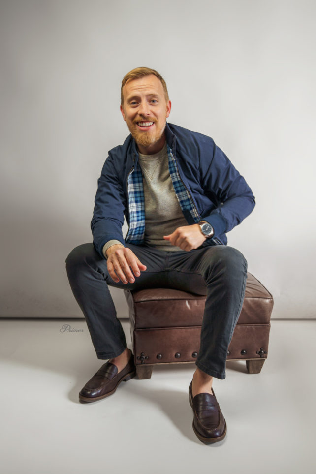 man wearing harrington jacket with gray sweatshirt, gray jeans, and penny loafers