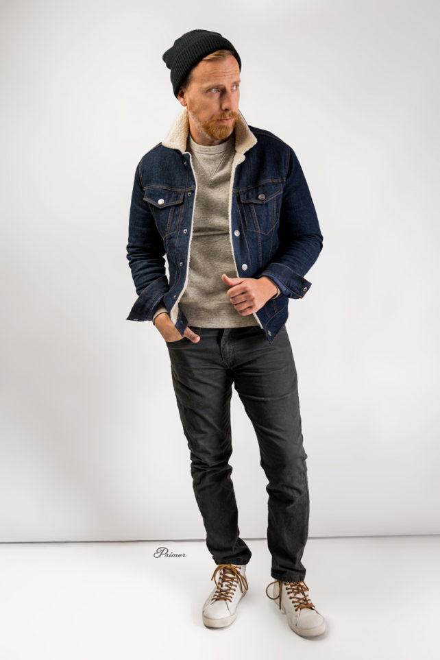 a photo example of a men's casual outfit featuring a shearling denim jacket, gray sweatshirt, gray jeans and sneakers.