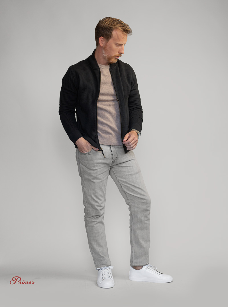 man wearing black bomber jacket with gray jeans and sneakers