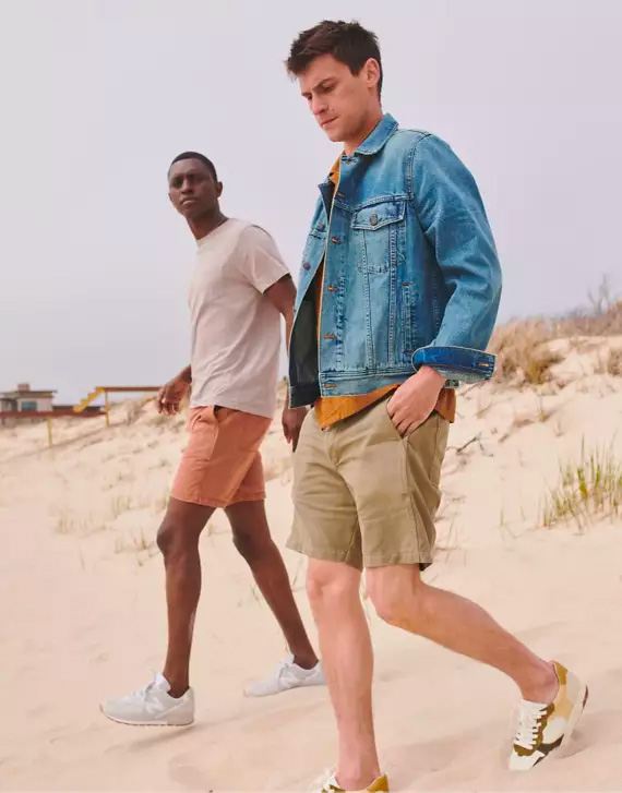 two men wearing casual summer outfits with shorts, shirts, and a denim jacket from Madewell