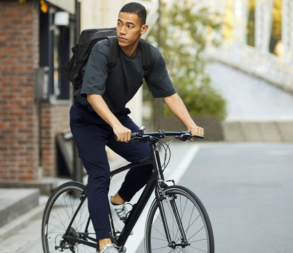 a man wearing a shirt and jeans from Uniqlo while riding a bicycle