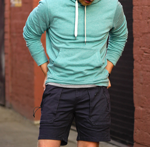 man wearing a light green hoodie style sweater and dark colored shorts