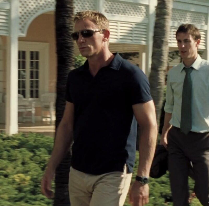 daniel craig james bond wearing a navy blue polo shirt and dark sunglasses