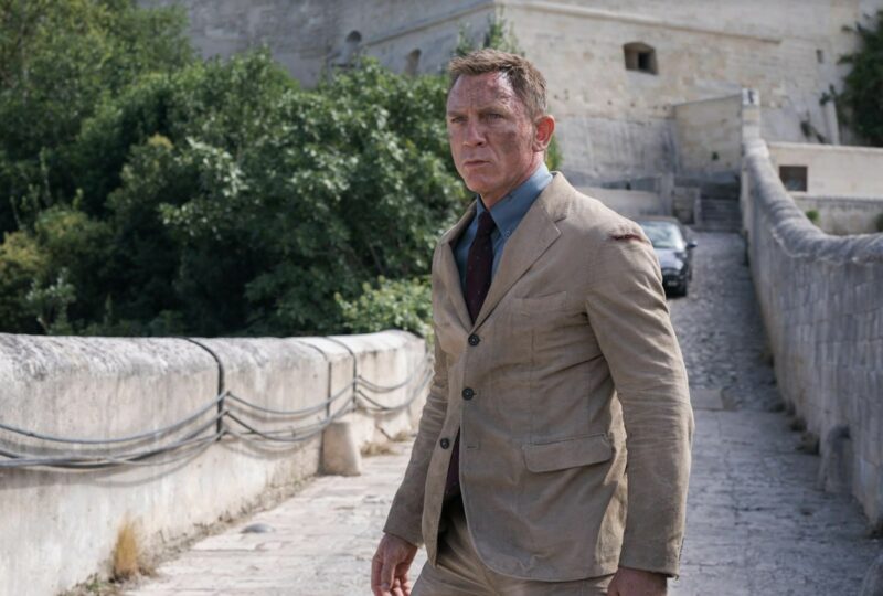 daniel craig james bond wearing a  tan suit and blue shirt