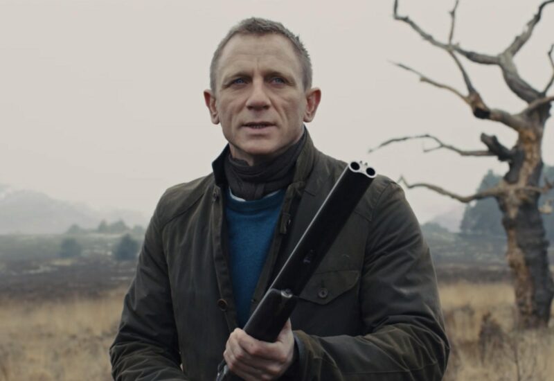daniel craig james bond wearing a waxed barbour jacket while outdoors and holding a firearm