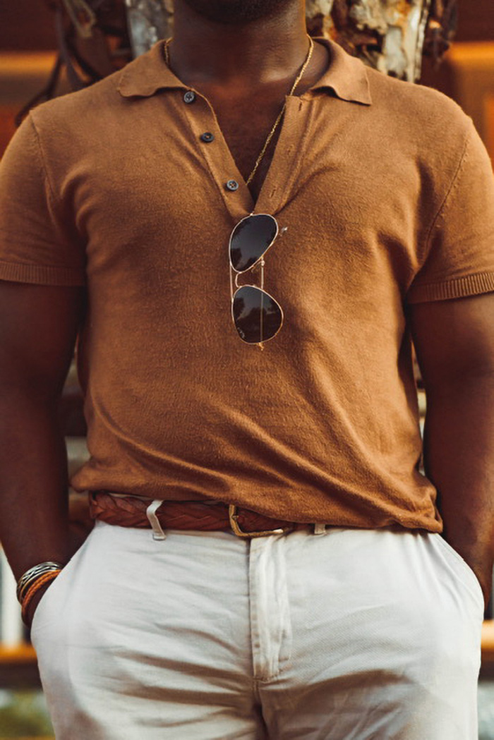close up of a man wearing a knit polo with sunglasses hanging from the collar