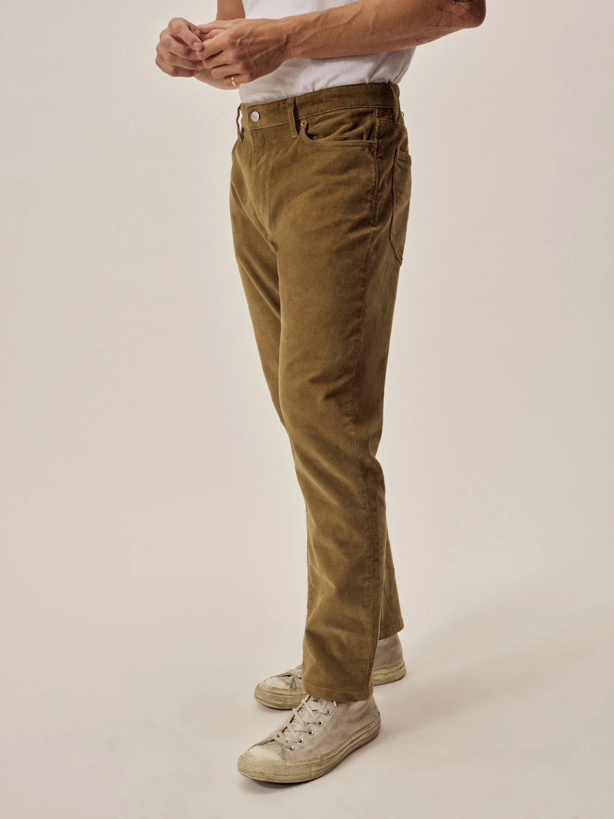 a person wearing corduroy pants with white lace up sneakers