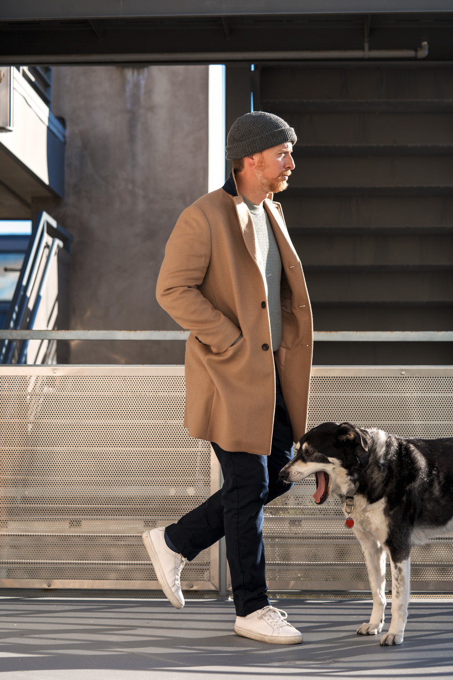 scandinavian men's style outfit inspiration with camel topcoat, sweater, watch cap, and white sneakers