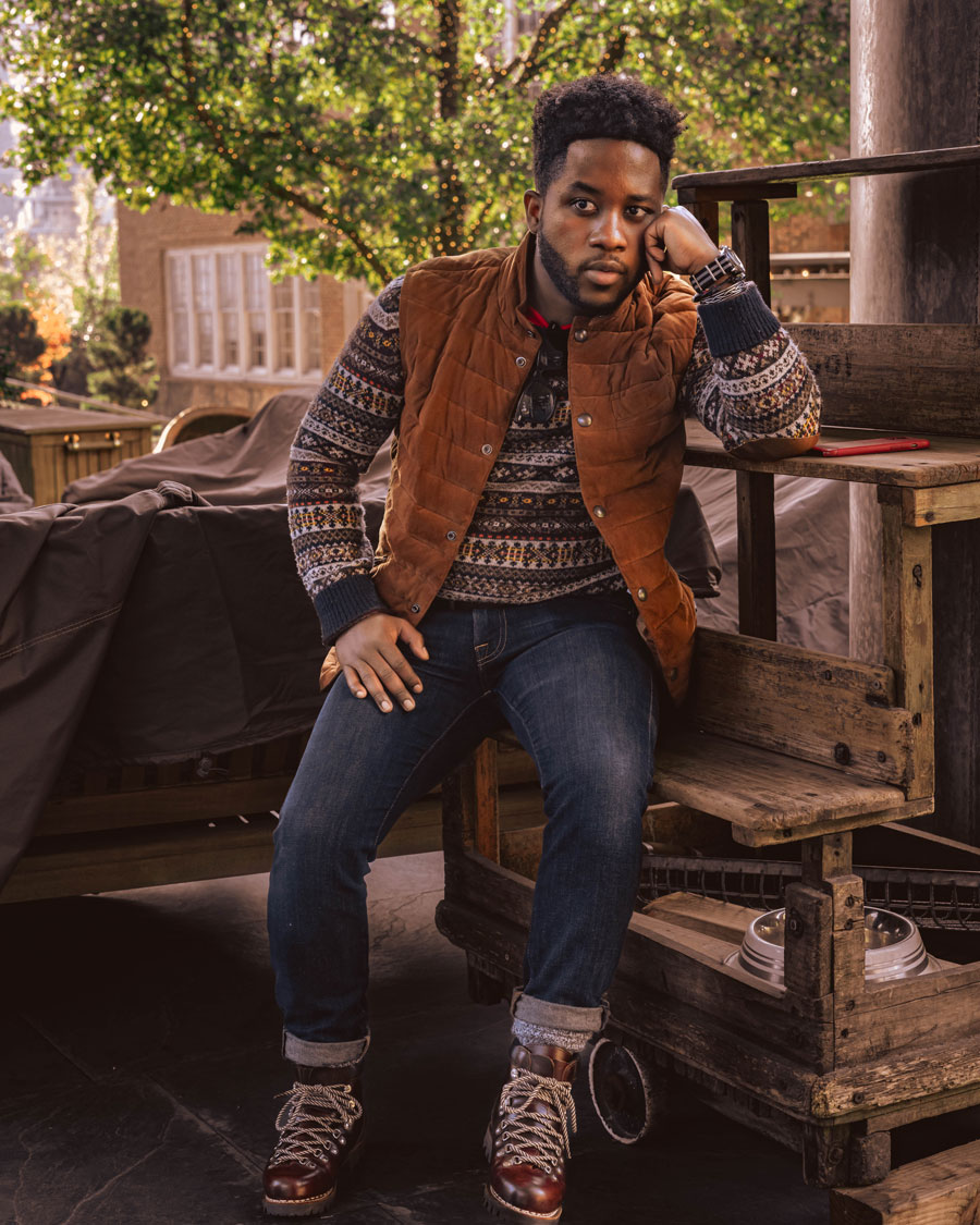 men's winter outfit idea with fair isle sweater, suede vest, dark jeans, and brown boots