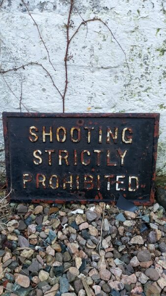 image of a cast iron sign that reads shooting strictly prohibited